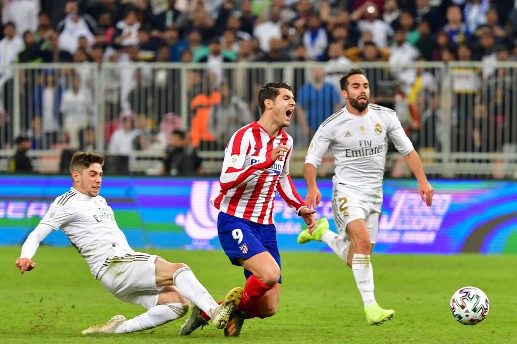 Real Madrid's Uruguayan midfielder Federico Valverde (L) fouls Atletico Madrid's Spanish forward Alvaro Morata (C) during the Spanish Super Cup final between Real Madrid and Atletico Madrid on January 12, 2020, at the King Abdullah Sports City in the Saudi Arabian port city of Jeddah. (Photo by Giuseppe CACACE / AFP)