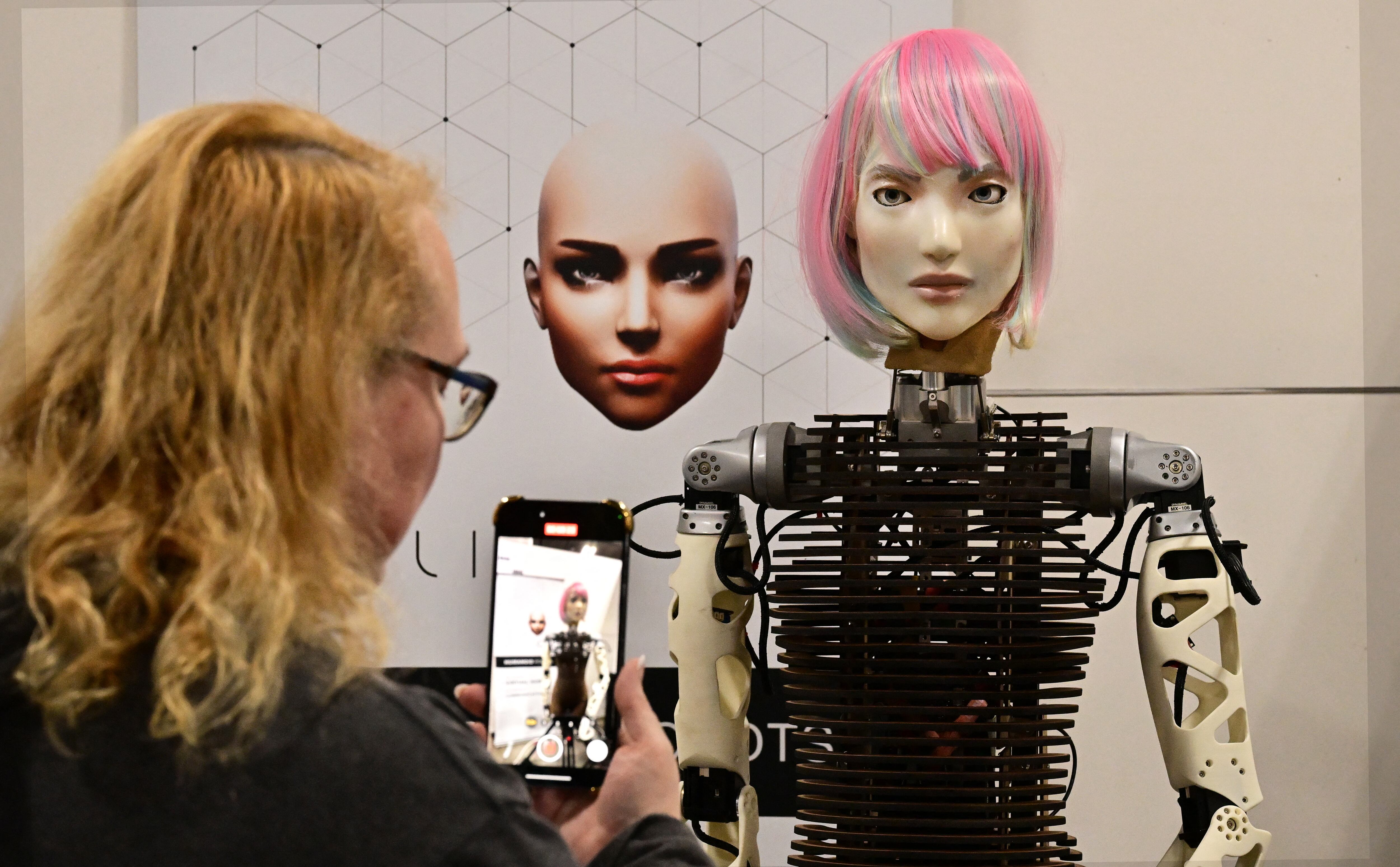 Una mujer fotografía un robot humanoide de AI Life con IA comunicativa de inspiración biológica. (Foto: AFP)