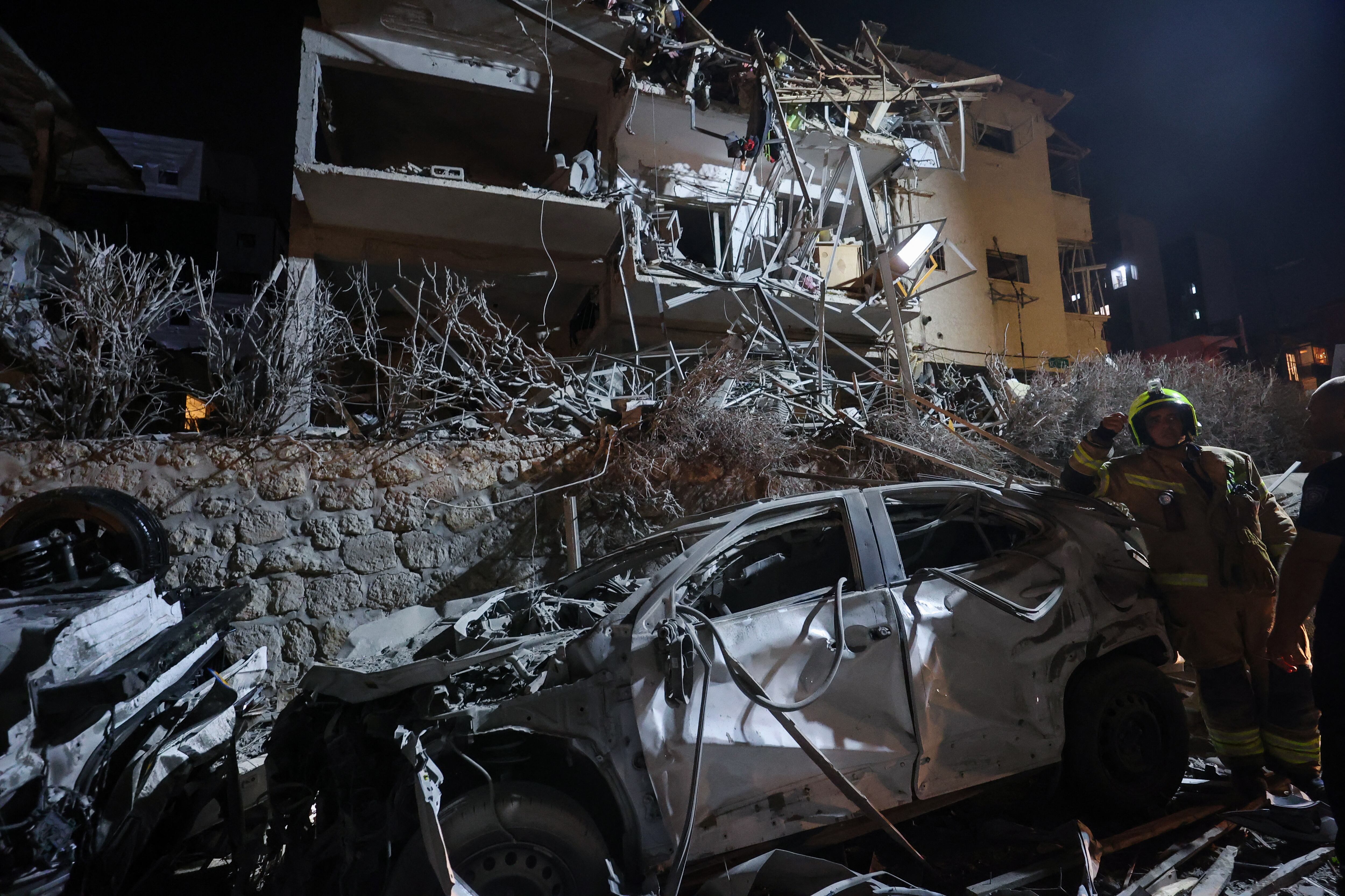 Un bombero israelí junto a un coche destrozado en un lugar alcanzado por un misil de Irán en Ramat Gan, a las afueras de Tel Aviv, el 13 de junio de 2025. (Foto de GIL COHEN-MAGEN / AFP).