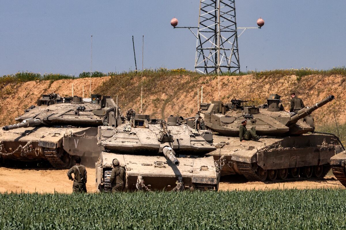 Soldados del ejército israelí junto a uno de varios tanques de batalla Merkava desplegados en una posición en el sur de Israel a lo largo del norte de la Franja de Gaza, el 18 de marzo de 2025. (Foto de Menahem KAHANA / AFP)