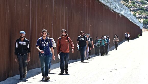 Migrantes caminan por el lado estadounidense del muro fronterizo en Jacumba Hot Springs, California, el 5 de junio de 2024, después de cruzar desde México. (Frederic J. BROWN / AFP).