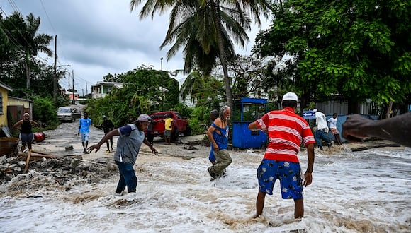 La gente camina entre las inundaciones causadas por el agua de mar después del paso del huracán Beryl en la parroquia de Saint James, Barbados, cerca de Bridgetown, Barbados, el 1 de julio de 2024. (Foto de CHANDAN KHANNA / AFP)