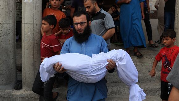 Un pariente lleva el cuerpo de un niño de la familia de Abu Quta. Diecinueve  integrantes de que misma familia murieron en los ataques israelíes contra la ciudad palestina de Rafah, en el sur de la Franja de Gaza. (Foto de SAID KHATIB / AFP).