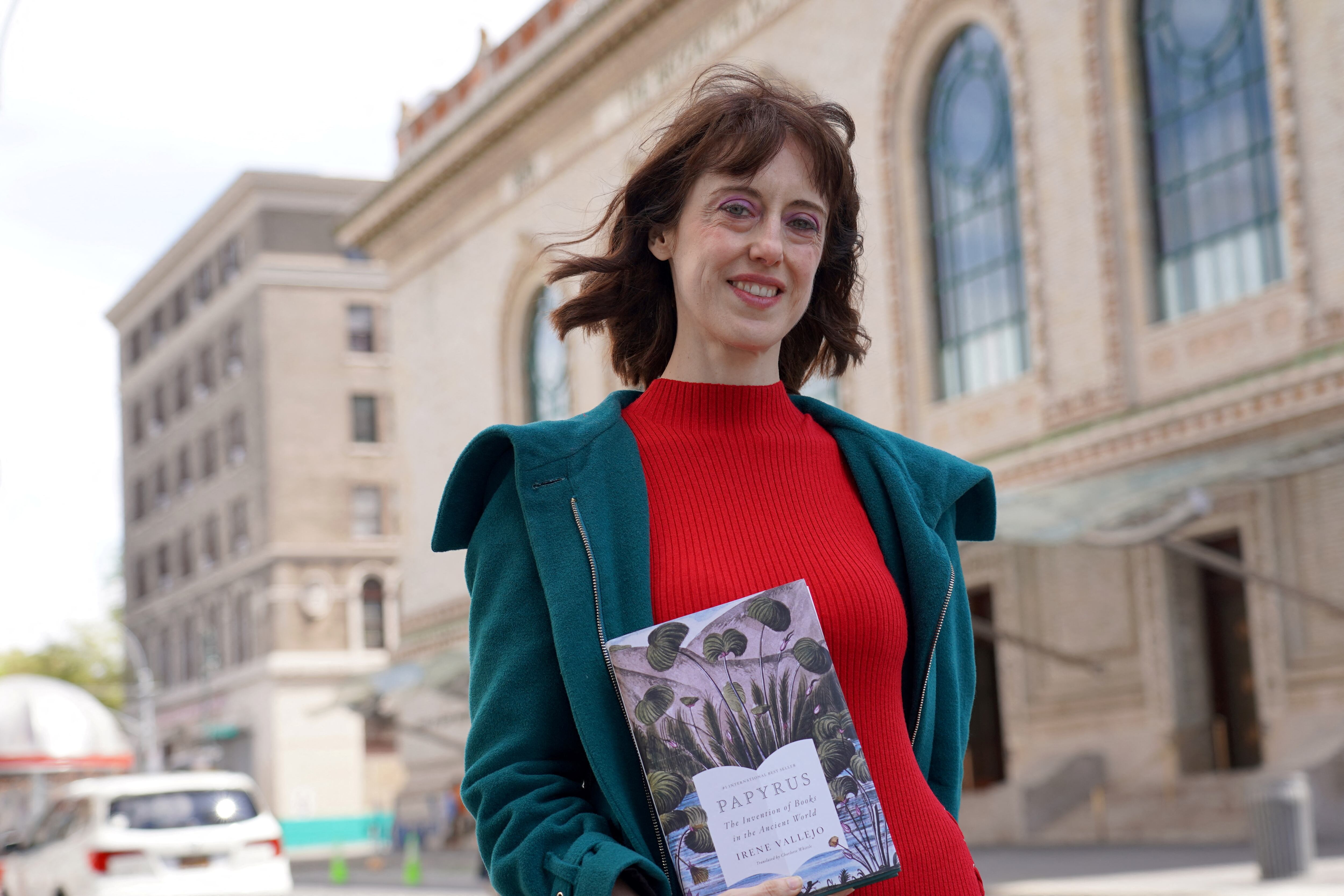 La autora española Irene Vallejo junto con una traducción al inglés de su libro "El infinito de un junco", libro sobre la historia de los libros. (Foto de Enrique Mora / AFP)