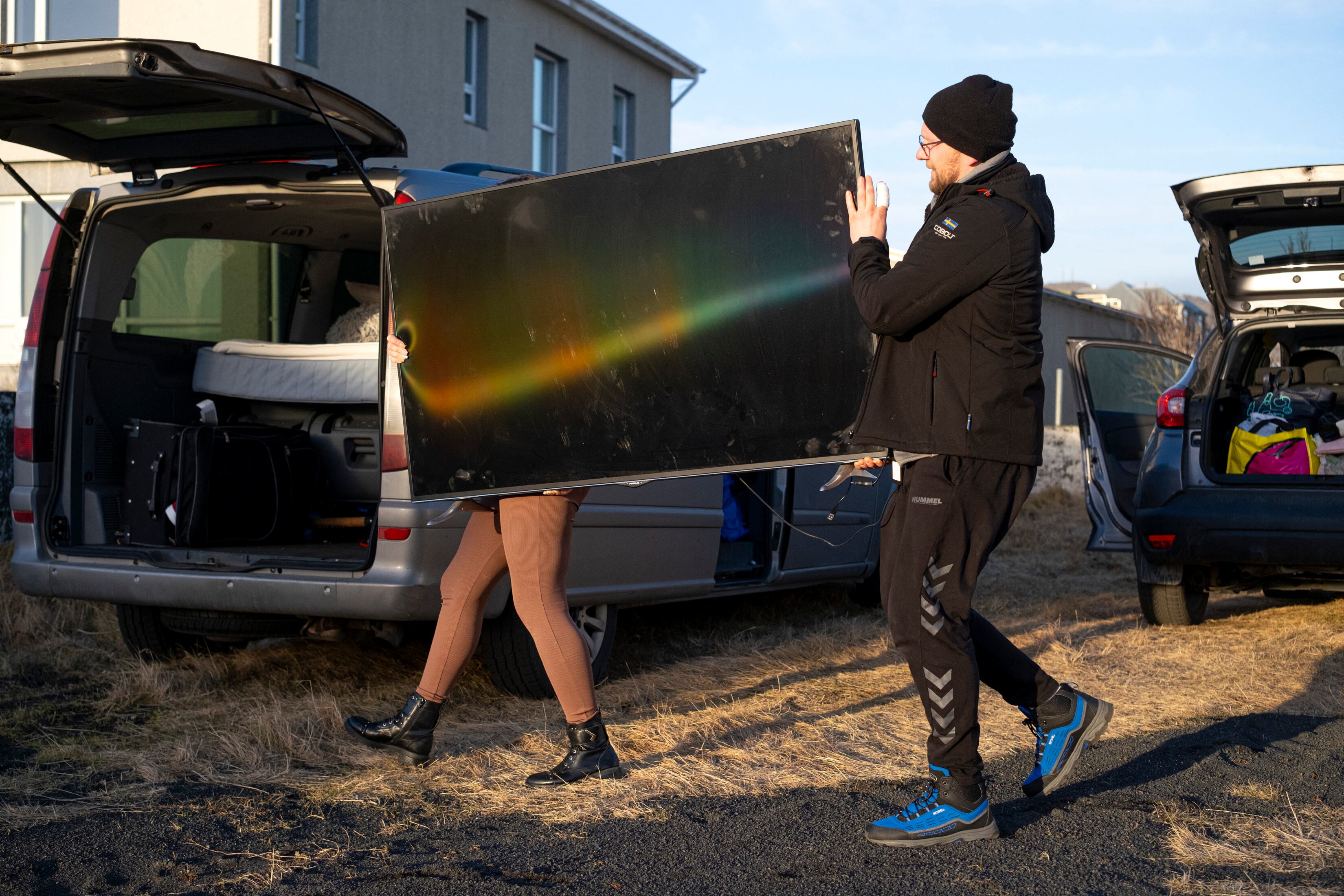 Esta foto tomada el 13 de noviembre de 2023 muestra a los habitantes cargando pertenencias desde sus hogares a un vehículo en Grindavik, suroeste de Islandia. (Foto de Kjartan TORBJOERNSSON / AFP).