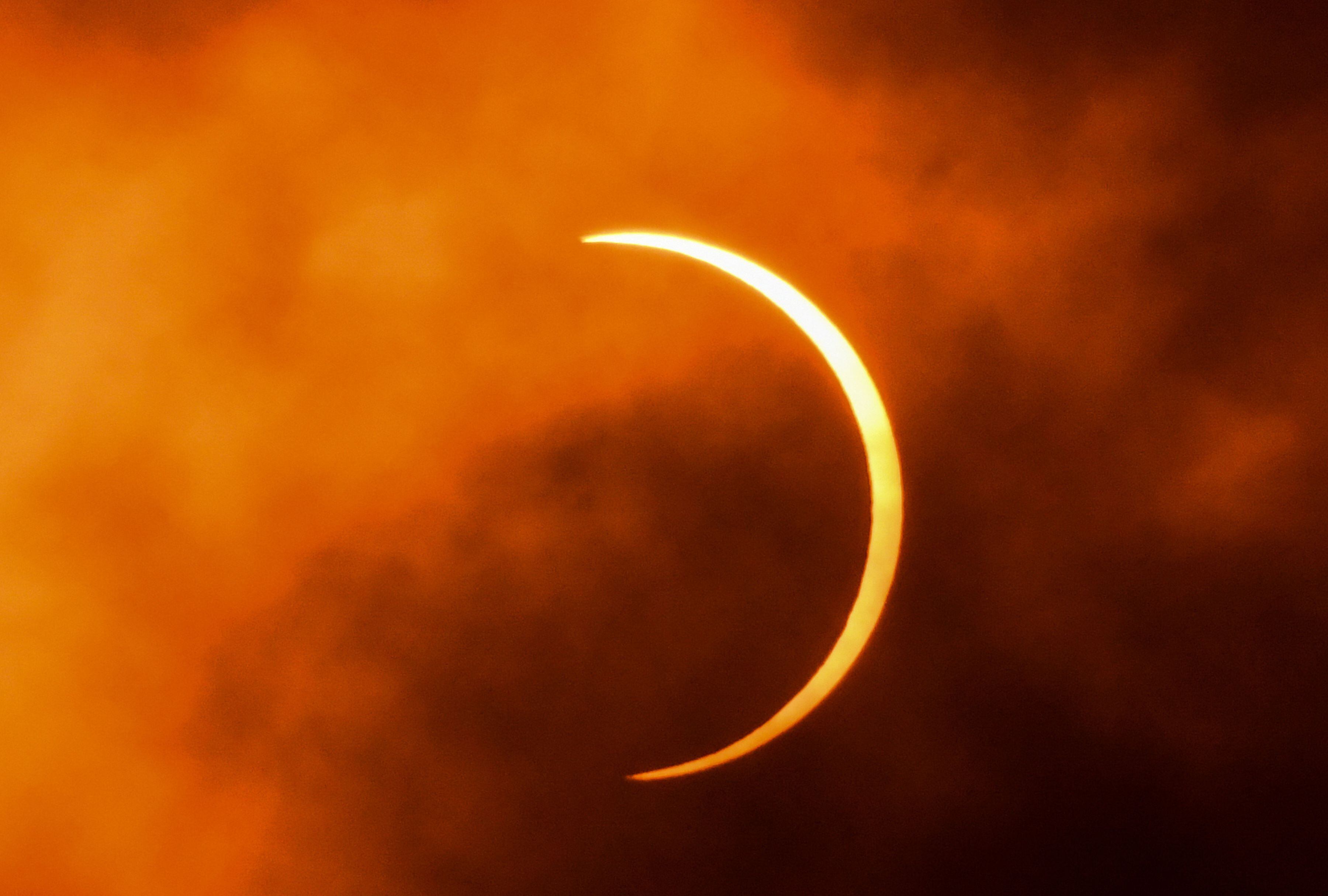 La Luna se mueve frente al Sol durante un eclipse solar anular visto a través de las nubes. (Foto: Jewel Samad / AFP)