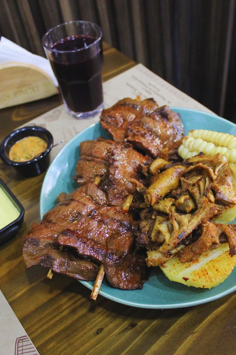 El especial de la casa combina anticucho de corazón de res, choncholí, rachi y pancita. Todo se sirve con rodajas de papa a la parrilla, choclo tierno y cremas como rocoto parrillero y ají de la casa.