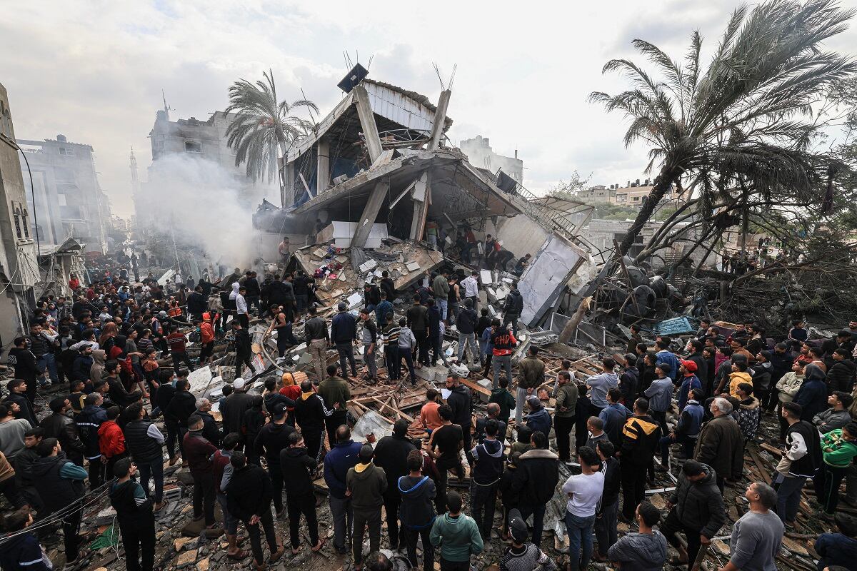 Palestinos se reúnen alrededor de la casa destruida de la familia Shehada tras el bombardeo israelí de Rafah, en el sur de la Franja de Gaza, el 14 de diciembre de 2023. (Foto de Mahmud HAMS / AFP)