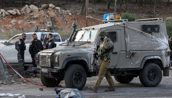 Un soldado israelí pasa junto a un cadáver en la escena de un ataque cerca del asentamiento judío de Eli en el norte de Cisjordania ocupada el 20 de junio de 2023. (Foto de AHMAD GHARABLI / AFP)