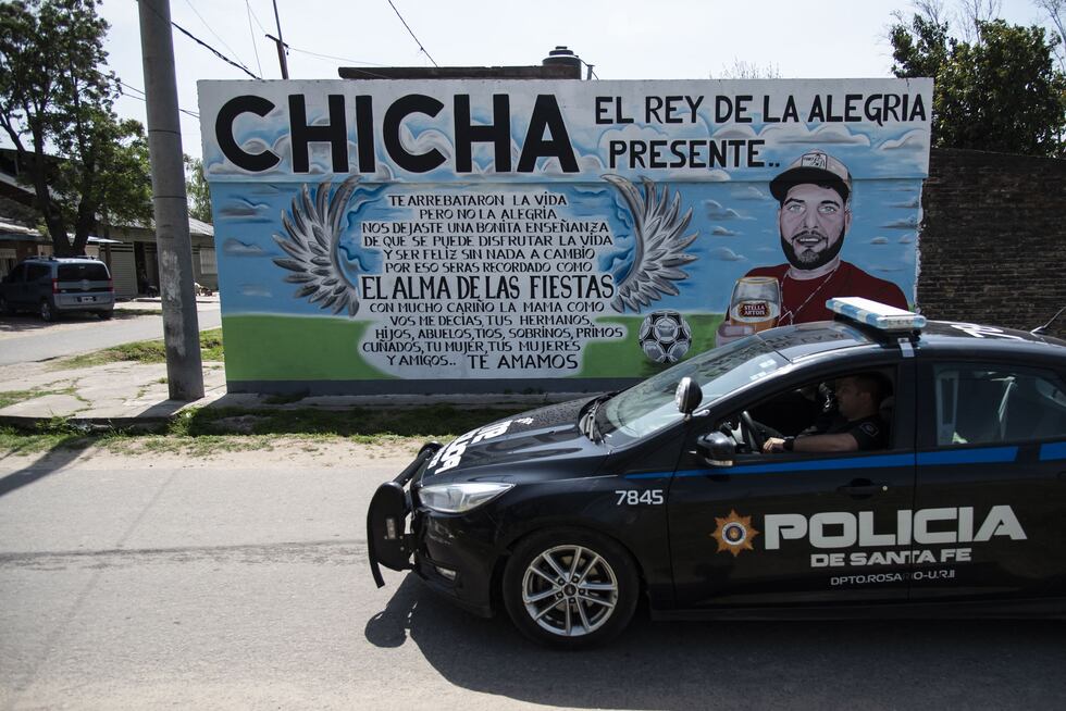 Un carro de policía pasa junto a un mural que representa a 'Chicha', víctima de la violencia en el barrio de las Flores, en Rosario, provincia de Santa Fe, el 2 de octubre de 2020. (Foto de MARCELO MANERA/AFP).