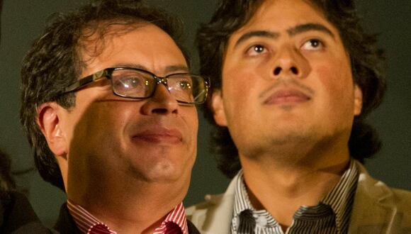 El presidente de Colombia, Gustavo Petro, saluda a sus simpatizantes mientras su hijo Nicolás Petro observa desde el balcón del ayuntamiento durante una manifestación en el centro de Bogotá el 13 de enero de 2014. (Foto de EITAN ABRAMOVICH / AFP)