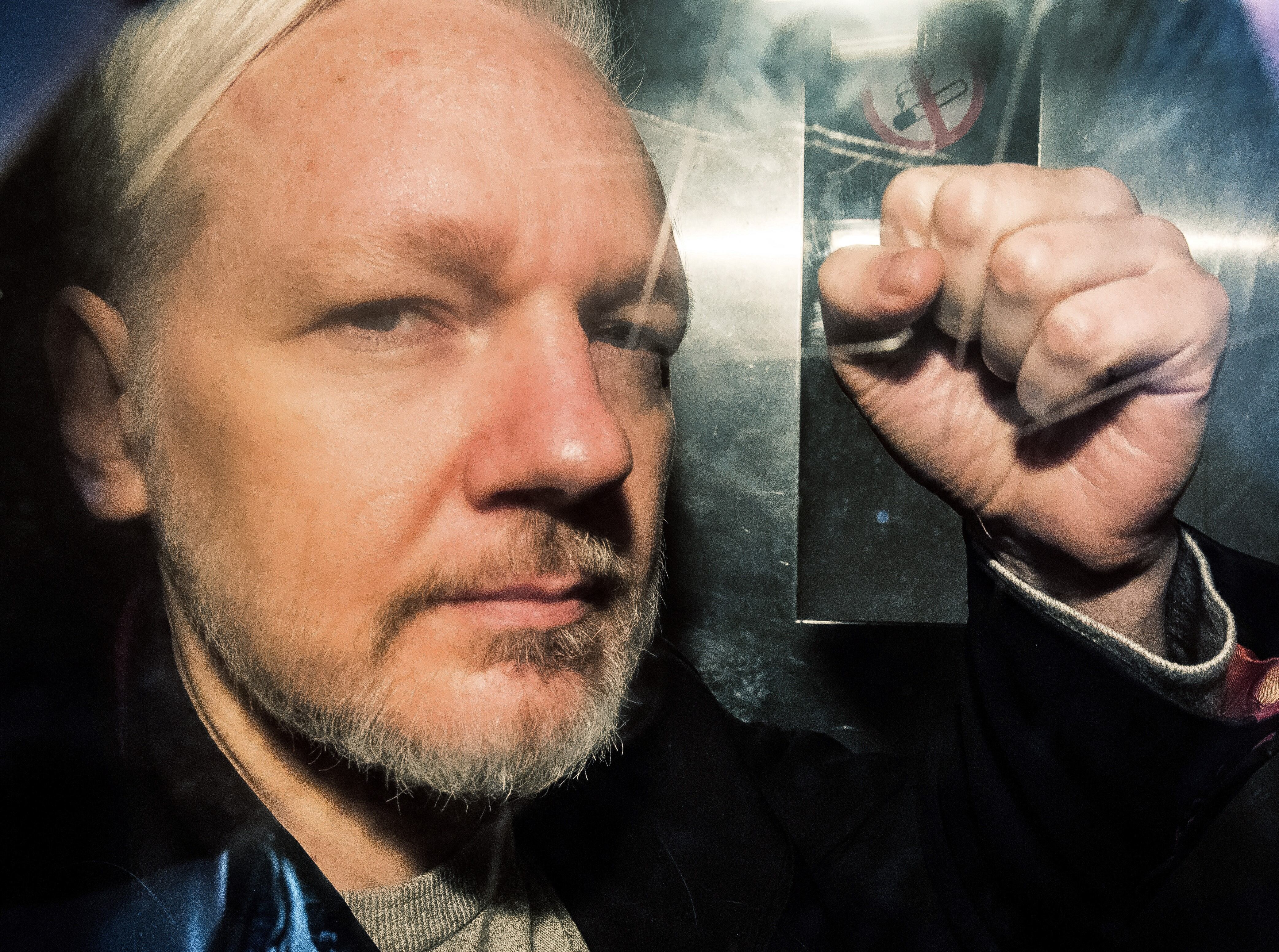 El fundador de WikiLeaks, Julian Assange, hace gestos desde la ventana de una camioneta de prisión mientras lo conducen al Tribunal de la Corona de Southwark, en Londres, el 1 de mayo de 2019. (Foto de Daniel LEAL / AFP).