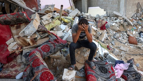Un joven palestino reacciona sentado sobre los escombros de una casa destruida tras un ataque militar israelí contra el campo de refugiados de Rafah, en el sur de la Franja de Gaza, el 15 de octubre de 2023. (Foto de MOHAMMED ABED / AFP)