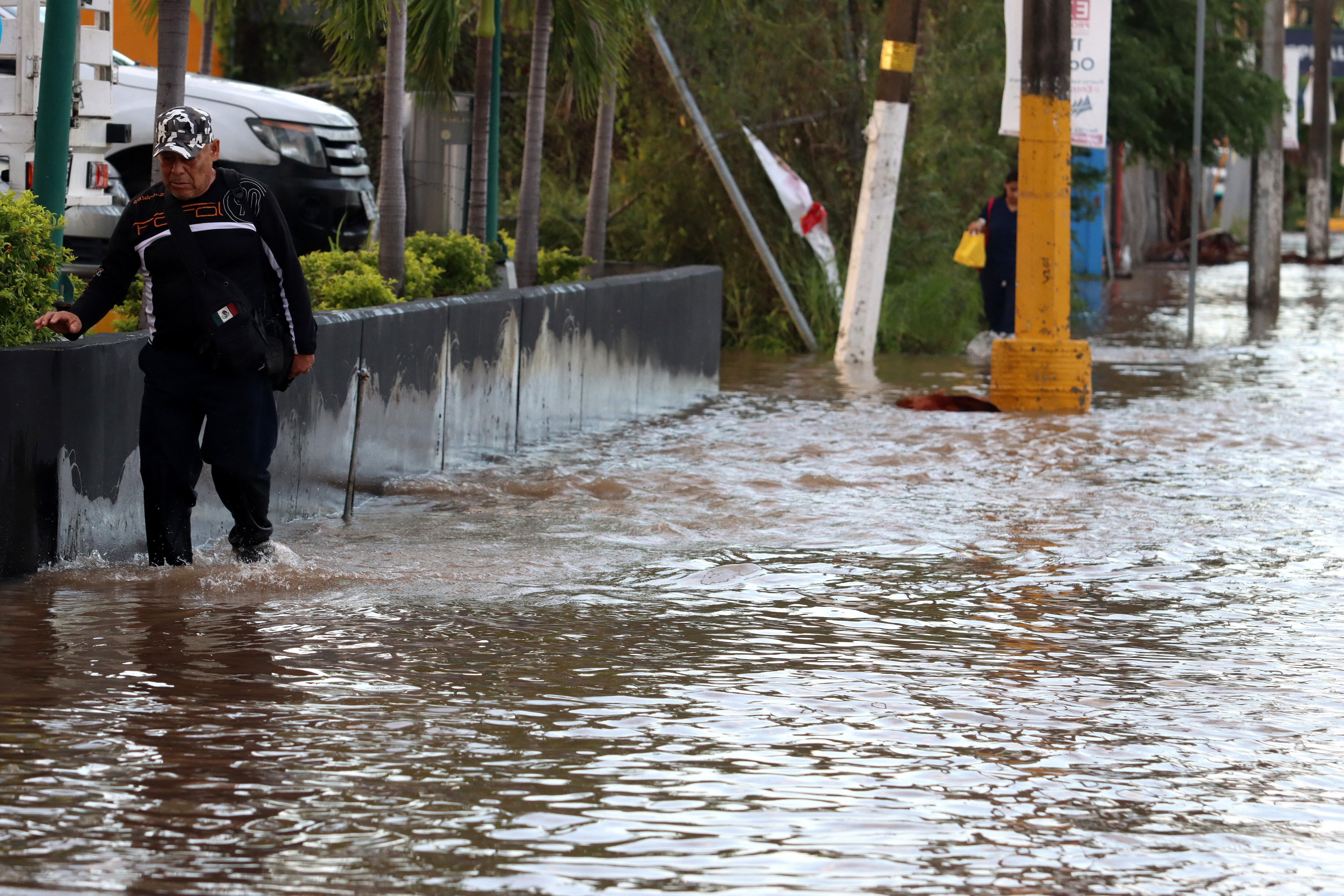 Un hombre camina por una calle inundada después del paso del huracán Lidia en Puerto Vallarta, estado de Jalisco, México, el 11 de octubre de 2023. (Foto de ULISES RUIZ / AFP).