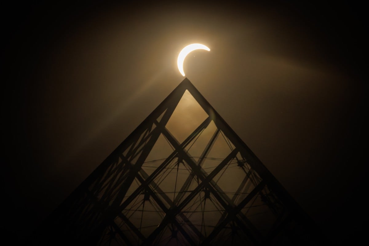 La luna pasa por el horizonte del sol detrás de la Pirámide del Louvre, diseñada por el arquitecto chino-estadounidense Ieoh Ming Pei, durante un eclipse solar parcial en París el 12 de agosto de 2026. En Francia, el eclipse solar no fue total; después del eclipse solar total de 1999, Francia no volverá a ver otro eclipse total hasta dentro de 55 años, en 2081. (Foto de Simon WOHLFAHRT / AFP) / USO EDITORIAL RESTRINGIDO - MENCIÓN OBLIGATORIA DEL ARTISTA AL PUBLICAR - PARA ILUSTRAR EL EVENTO TAL COMO SE ESPECIFICA EN EL PIE DE FOTO