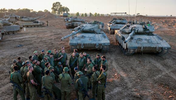 Soldados israelíes desplegados en la frontera sur con la Franja de Gaza el 29 de noviembre de 2023, se reúnen para una sesión informativa junto a tanques de batalla, cuando la tregua entre Israel y Hamás entró en el sexto día después de que se ampliara un acuerdo para permitir nuevas liberaciones de rehenes israelíes y Prisioneros palestinos. (Foto de Menahem KAHANA / AFP)