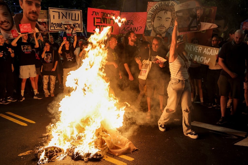 Manifestantes se congregan ante una hoguera durante una protesta antigubernamental para exigir la liberación de los rehenes israelíes secuestrados en la Franja de Gaza desde octubre del 2023. Foto: Jack GUEZ / AFP