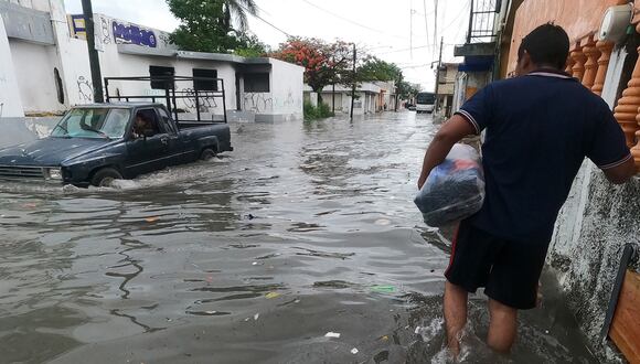 Un hombre y vehículo circulan por una calle inundada debido a las fuertes lluvias, en Cancún, estado de Quintana Roo, México, el 18 de junio de 2024. (Foto de Alonso Cupul / EFE)