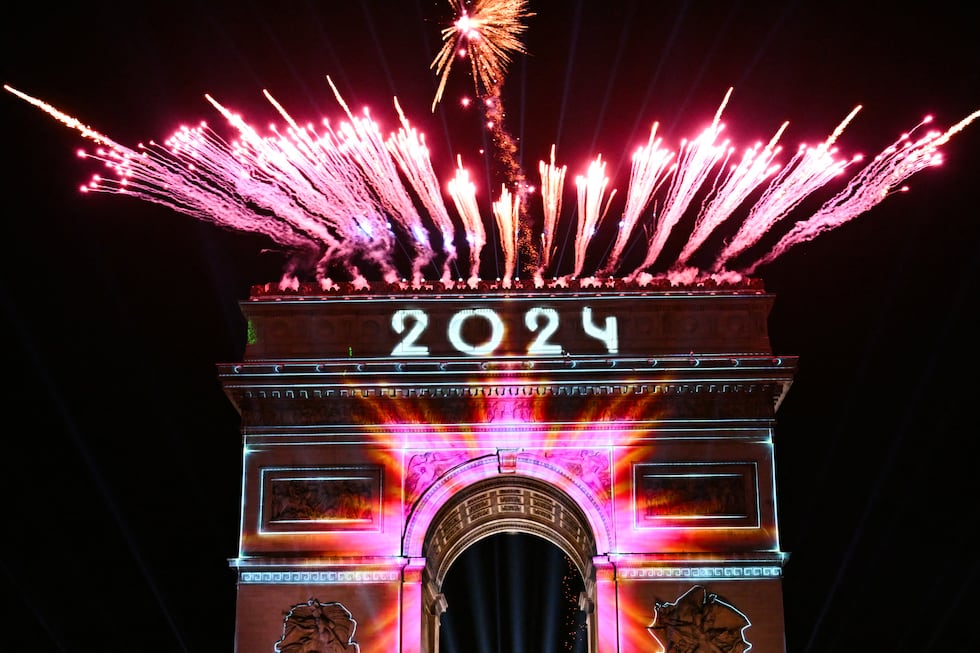 Los fuegos artificiales explotan junto al Arco de Triunfo con la palabra "2024" proyectada, en la Avenida de los Campos Elíseos, durante las celebraciones del Año Nuevo en París, Francia, a primera hora del 1 de enero de 2024. (Foto de Bertrand GUAY / AFP).