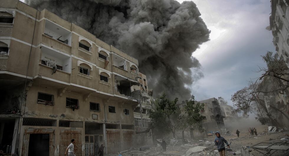 Los palestinos se apresuran a buscar refugio mientras se eleva el humo después del bombardeo de Israel en el centro de la ciudad de Gaza el 18 de marzo de 2024. (Foto de AFP).