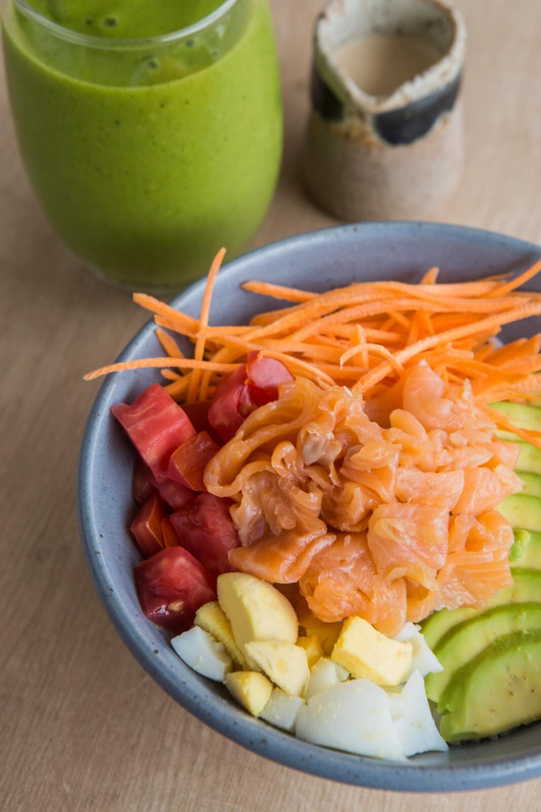 Un bowl de trucha ahumada con zanahoria, palta, tomate, huevo y base de arroz con salsa acebichada