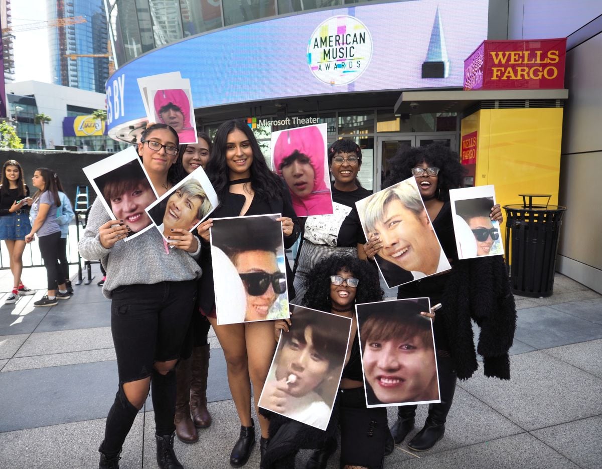 Los fanáticos del grupo BTS posan con fotos de sus ídolos fuera de los American Music Awards 2017, el 19 de noviembre de 2017 en el Microsoft Theatre de LA Live, en Los Ángeles, California (Foto: Robyn Beck / AFP)