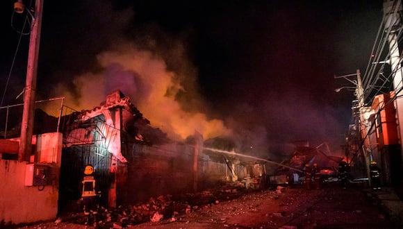 Bomberos trabajan para extinguir un incendio tras una explosión en un establecimiento comercial en San Cristóbal, República Dominicana, el 14 de agosto de 2023. (Foto de stringer / AFP)