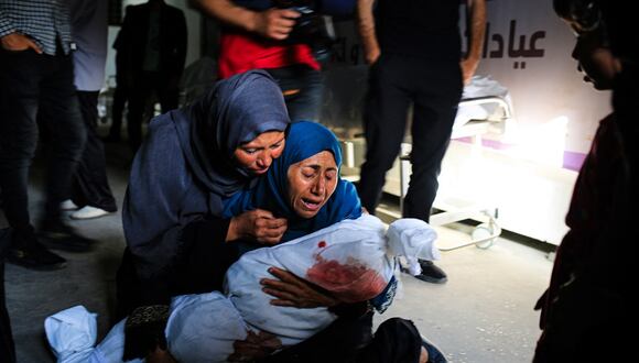 Una mujer palestina sostiene el cuerpo amortajado de un niño muerto en un bombardeo israelí, en una clínica de salud en el área de Tel al-Sultan en Rafah, en el sur de la Franja de Gaza, el 26 de mayo de 2024. (Foto de Eyad BABA / AFP)