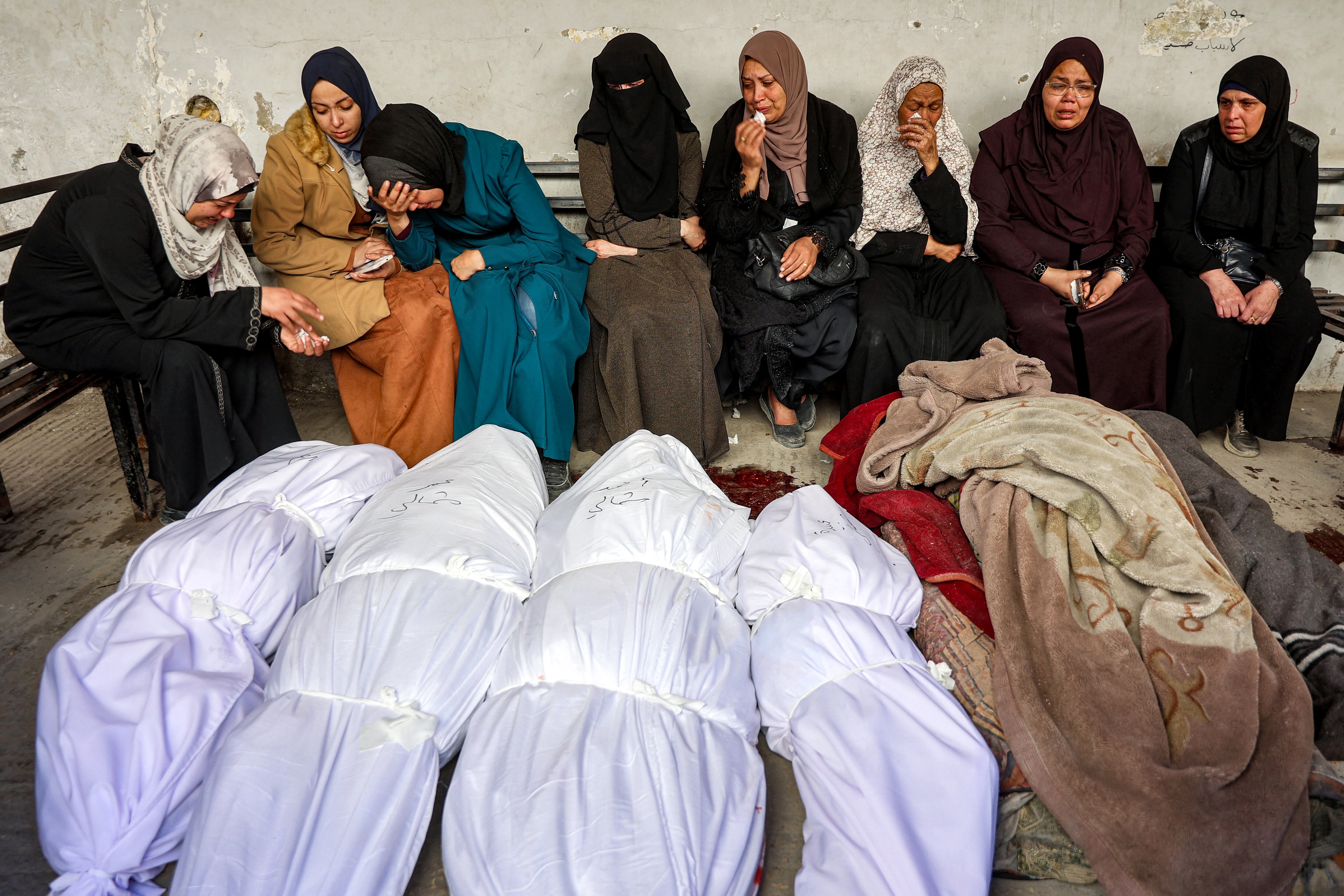 Mujeres sentadas juntas en señal de duelo junto a los cuerpos amortajados de las víctimas del bombardeo de Israel en la ciudad de Gaza, el 18 de marzo de 2025. (Foto de Omar AL-QATTAA / AFP).