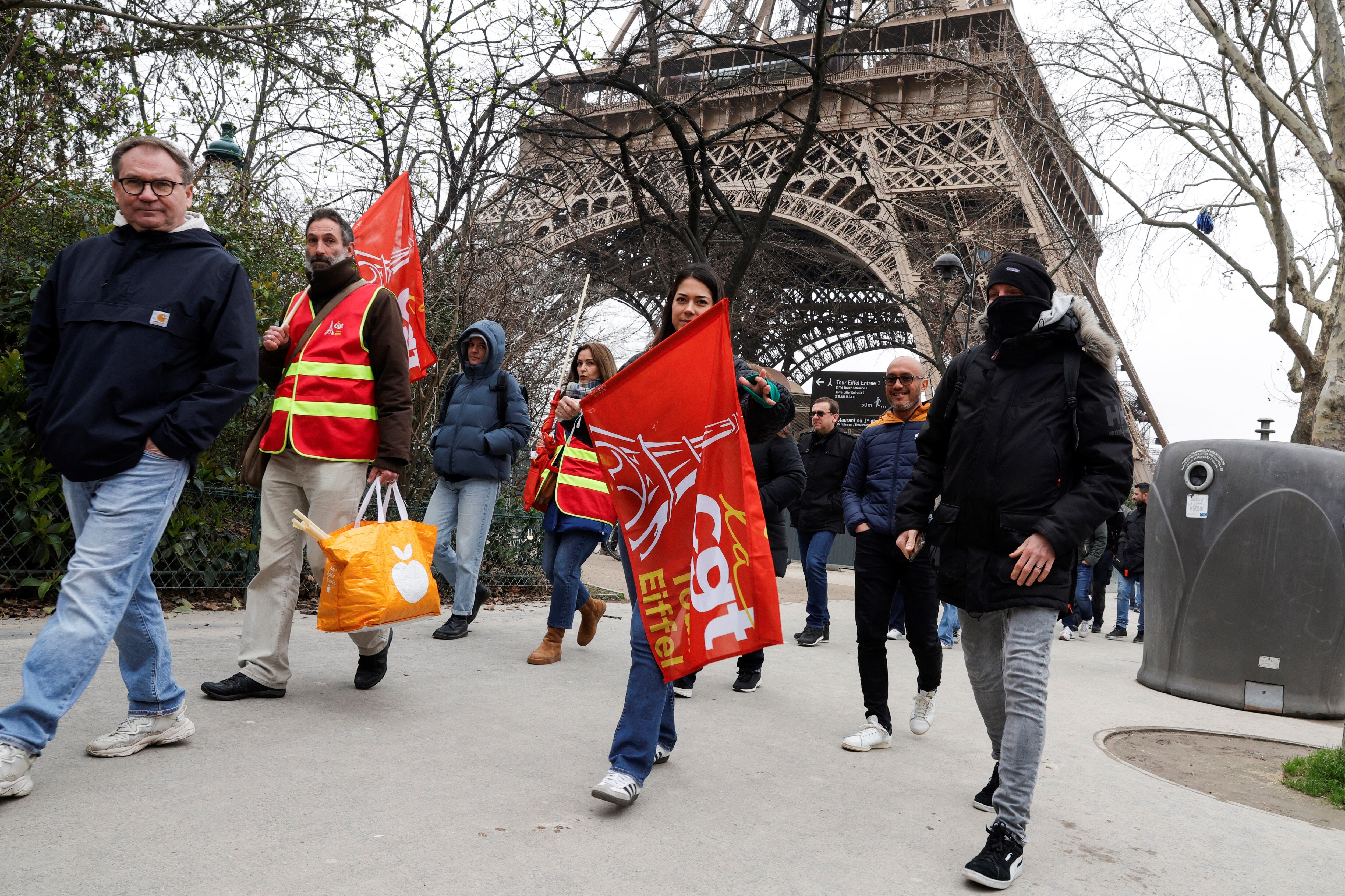 Los manifestantes sostienen banderas de los sindicatos CGT durante una huelga del personal de la Torre Eiffel, por la gestión financiera del monumento por parte de la ciudad, cerrando el monumento al público durante la segunda semana de las vacaciones escolares francesas, en París el 20 de febrero de 2024. (Foto de Geoffroy VAN DER HASSELT / AFP)