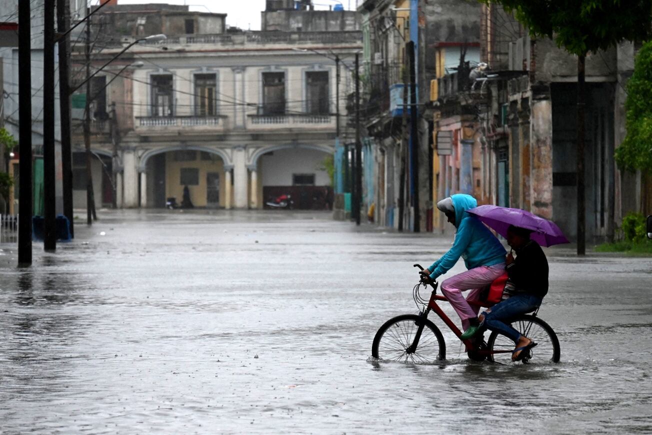 Dos personas andan en bicicleta por una calle inundada en La Habana, Cuba, el 29 de agosto de 2023, durante el paso del huracán Idalia. (Foto de Yamil LAGE / AFP).