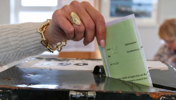 Una isleña deposita su voto dentro de la mesa electoral instalada en la sala de estar de un isleño, uno de los 28 registrados para votar, en la isla de Gola, frente a la costa de Donegal, en el oeste de Irlanda, mientras se lleva a cabo la votación en el referéndum sobre la constitución irlandesa en marzo. (Foto de PAUL FE / AFP)