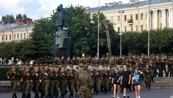 Cadetes de la Academia de Artillería Militar Mikhailov marchan frente a una estatua del fundador de la Unión Soviética Vladimir Lenin en San Petersburgo el 29 de agosto de 2023. (Foto de Olga MALTSEVA / AFP)