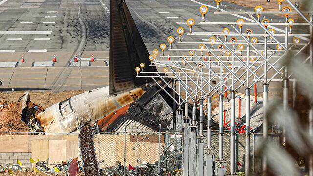 La sección de cola destrozada del avión Boeing 737-800 de Jeju Air que se estrelló y estalló en llamas se ve al final de la pista del Aeropuerto Internacional de Muan, en Corea del Sur. (Foto de YONHAP / AFP).