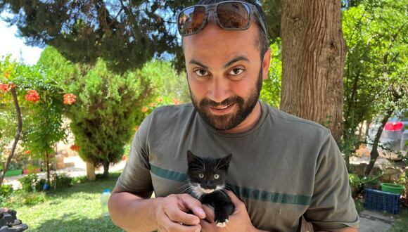 Esta imagen proporcionada por cortesía de Reuters muestra al periodista de Reuters Issam Abdallah sosteniendo un gatito mientras posa para una fotografía en Saaideh, Líbano, el 4 de julio de 2023. (Photo by Emilie MADI / courtesy of Reuters / AFP)