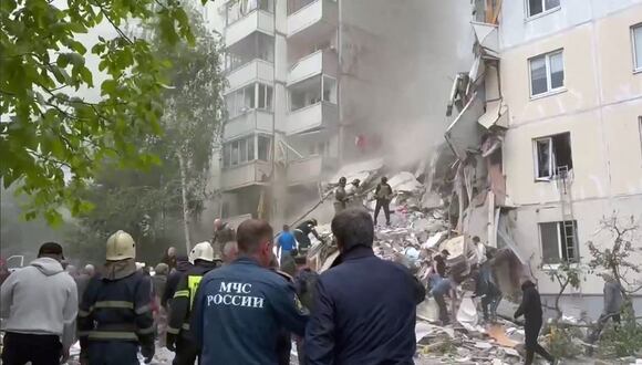 Personas y bomberos limpiando escombros en el lugar de un edificio de apartamentos que se derrumbó parcialmente tras haber sido dañado por un ataque ucraniano en Belgorod, el 12 de mayo de 2024. (Foto de Handout / Telegram @vvgladkov / AFP)