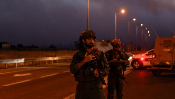 Soldados israelíes aseguran una carretera mientras se elevan nubes de humo después del lanzamiento de cohetes desde el sur del Líbano en los Altos del Golán anexados por Israel el 9 de julio de 2024. (Foto de Jalaa MAREY / AFP)