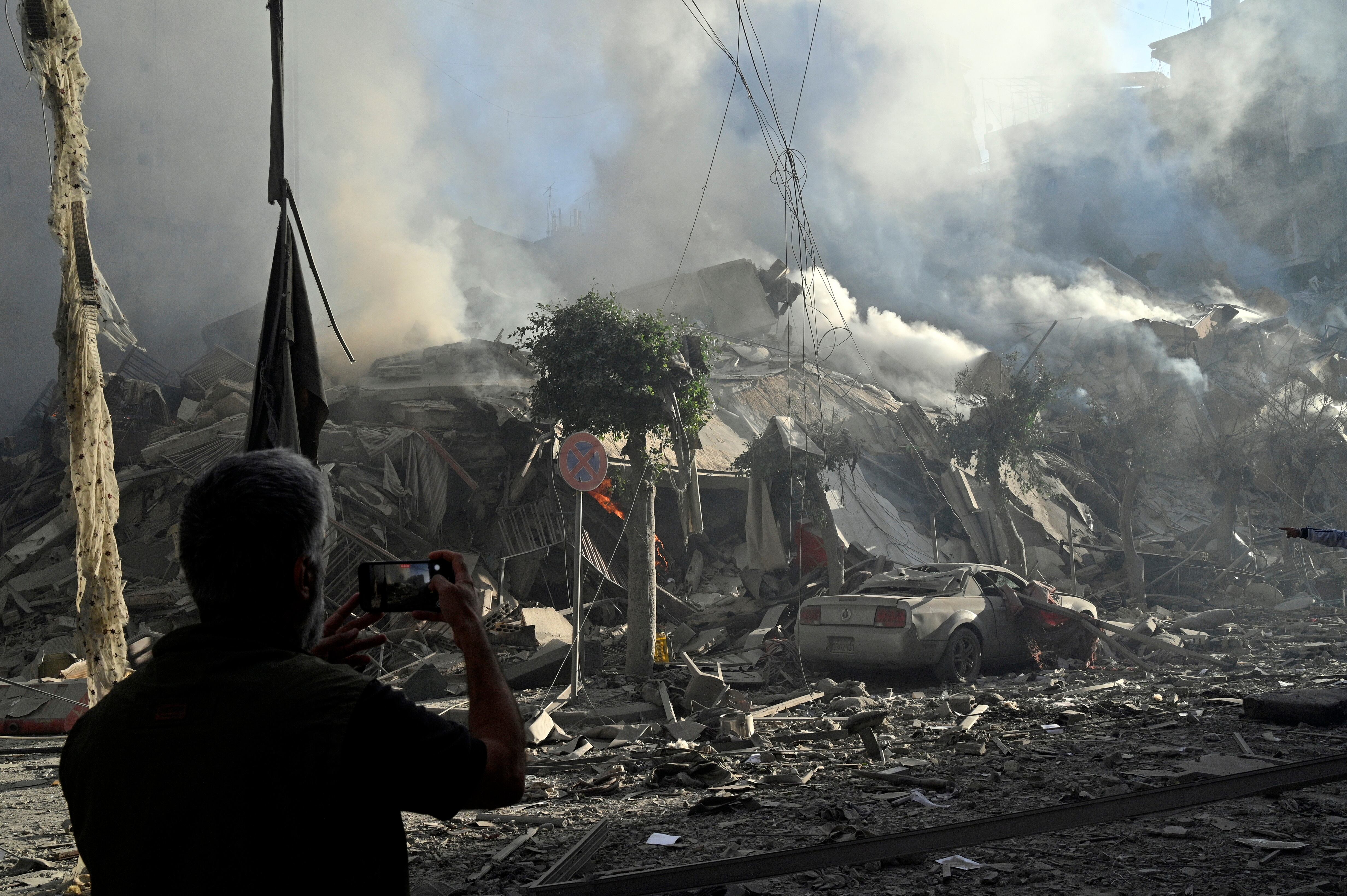 Un hombre fotografía un edificio humeante después de un ataque aéreo israelí sobre el barrio de Dahieh, uno de los bastiones de Hizbulá, en Beirut (El Líbano) estes jueves. (Foto: EFE/ Wael Hamzeh)