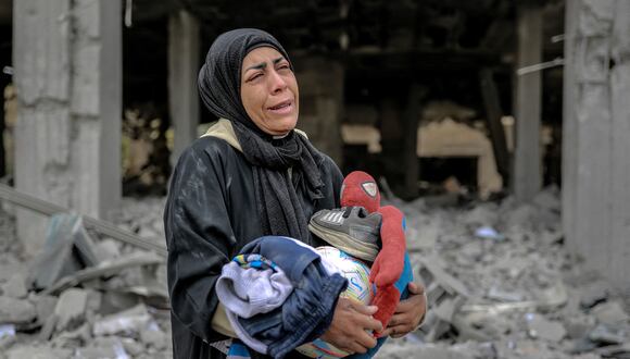 Una mujer palestina reacciona mientras sostiene sus pertenencias junto a los escombros de un edificio, después de que fuera destruido en un ataque israelí la noche anterior, en el barrio Rimal de la ciudad de Gaza el 16 de marzo de 2024, en medio de las batallas en curso entre Israel y los palestinos. (Foto de AFP)