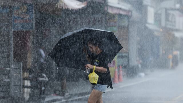 Una mujer camina con un paraguas durante una fuerte lluvia cerca del puerto de Su-ao en Yilan mientras el tifón Haikui toca tierra en el este de Taiwán el 3 de septiembre de 2023. (Foto de I-Hwa Cheng / AFP).