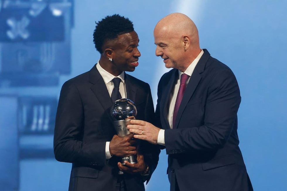 Brazilian forward Vinicius Junior (L) receives the Best Player trophy from FIFA President Gianni Infantino during the Best FIFA Football Awards 2024 ceremony in Doha on December 17, 2024. (Photo by Karim JAAFAR / AFP)