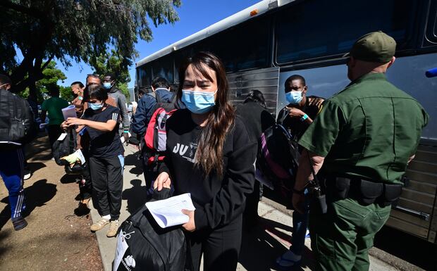 Un oficial de la Patrulla Fronteriza de Estados Unidos observa cómo los migrantes de China y África se bajan de un autobús al llegar a una estación de tren de San Diego, California, el 10 de octubre de 2023. (Foto de Frederic J. BROWN / AFP).