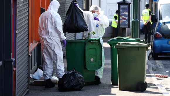 Los oficiales forenses de la policía buscan en los contenedores afuera de una tienda en Ilkeston Road en Nottingham, en el centro de Inglaterra, luego de un "incidente importante" en el que tres personas fueron encontradas muertas. (Foto de Darren Staples/AFP)