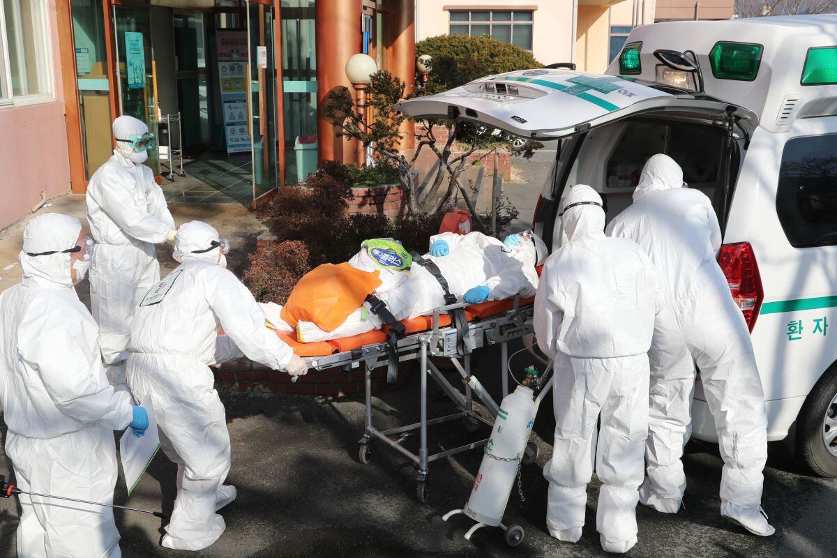 Los trabajadores médicos usan equipos de protección para transferir a un paciente sospechoso de coronavirus a otro hospital desde el Hospital Daenam, en el condado de Cheongdo, cerca de la ciudad de Daegu, en el sureste de Corea del Sur (Foto: AFP)