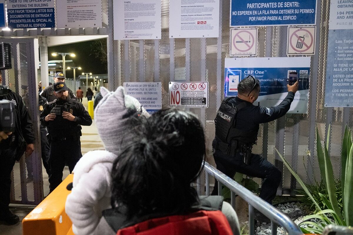 Un oficial de policía local escanea el código QR de la aplicación CBP One en la frontera entre Estados Unidos y México, visto desde Tijuana, estado de Baja California, México, el 11 de mayo de 2023 (Foto: Guillermo Arias / AFP)
