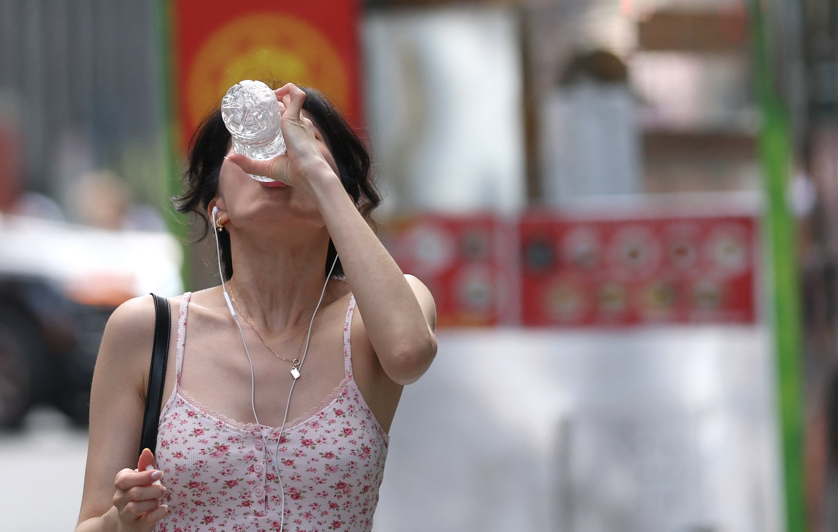 Una ciudadana de Nueva York caminando por una conocida avenida mientras se hidrata para evitar mayores estragos por el aumento de temperaturas (Foto: AFP)