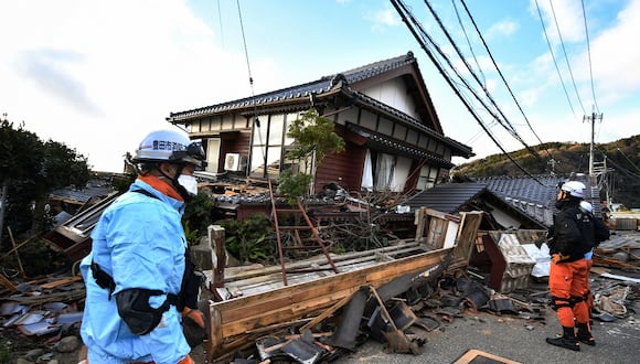 Bomberos inspeccionan casas de madera derrumbadas en Wajima, prefectura de Ishikawa, el 2 de enero de 2024, un día después de que un gran terremoto de magnitud 7,5 sacudiera la región de Noto. (Foto de Kazuhiro NOGI / AFP)
