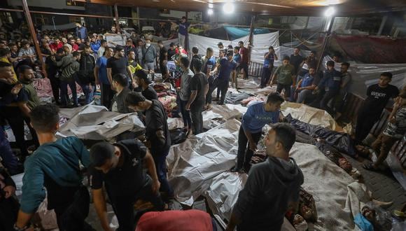 Gente se reúne alrededor de los cuerpos de los palestinos muertos después de que un ataque arrasara el hospital Ahli Arab en el centro de Gaza después de que fueron transportados al hospital Al-Shifa, el 17 de octubre de 2023. (Foto de Dawood NEMER / AFP)