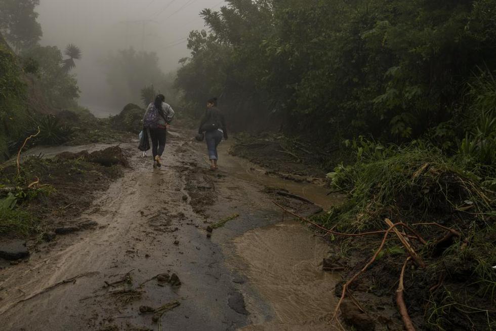 Mujeres caminan por un camino con lodo hacia Comasagua, El Salvador, el lunes 10 de octubre de 2022, tras el paso del huracán Julia. (Foto AP/Moisés Castillo).
