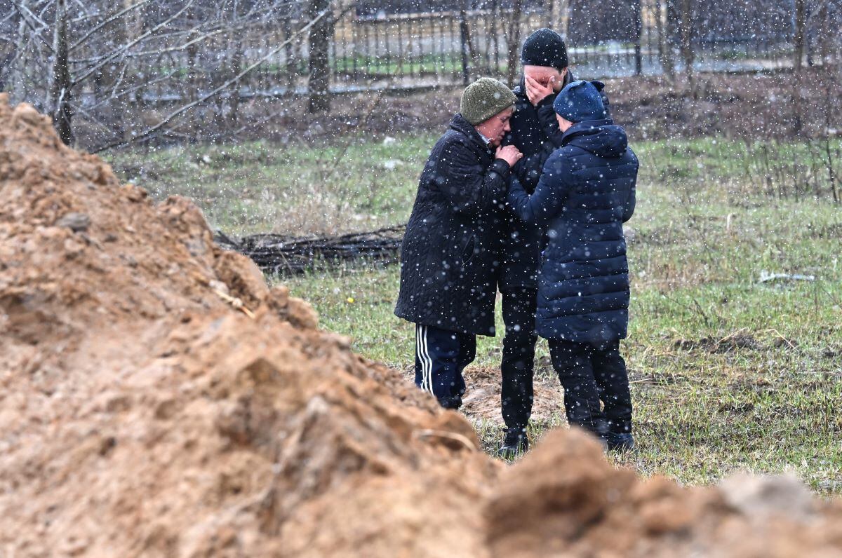 People react as they gather near a mass grave in the city of Bucha, northwest of Ukraine's capital kyiv, on April 3, 2022. (Sergei SUPINSKY/AFP)